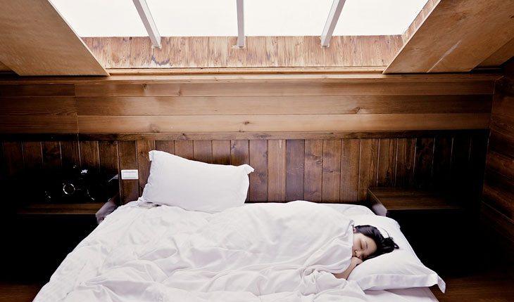 Como aliviar a tpm. Na foto, uma mulher dormindo debaixo de um cobertor branco