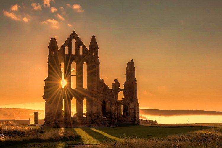 Na imagem, uma igreja de pedra está em ruínas com o sol por trás de uma janela. Construir sua igreja. 