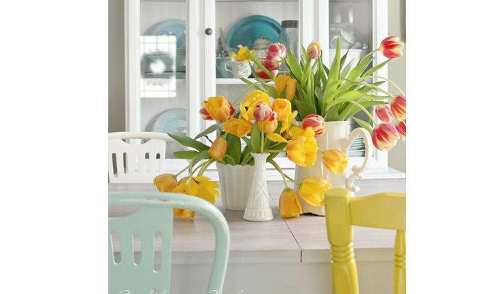 Na foto há uma mesa com vasos com flores em cima.
