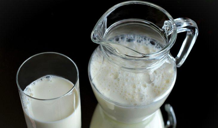 Na foto há uma jarra e um copo com leite