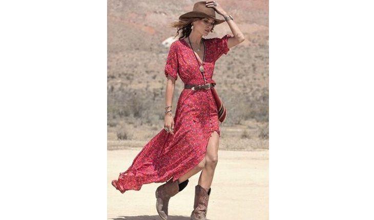 Na foto há uma mulher usando bota estilo cowboy com um vestido vermelho e um chapéu