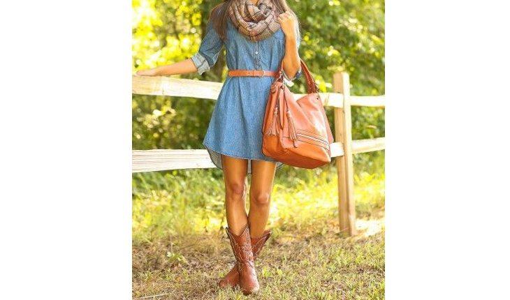 Na foto há uma mulher usando bota estilo cowboy com um vestido azul e uma bolsa da mesma cor que a bota.