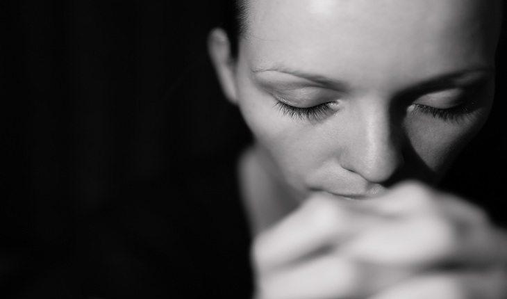 mulher com os olhos fechados e as mãos em posição de oração