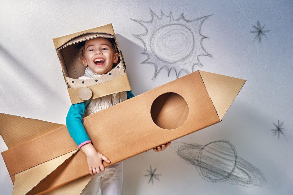 Natureza, imagem de um garoto brincando de astronauta em um foguete feito de papelão.