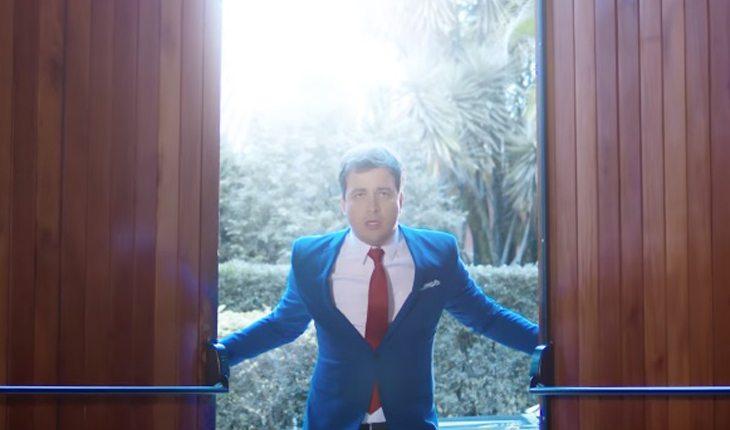 Na foto há o ator Rafael Cortez vestido de noivo abrindo a porta de madeira de uma igreja.