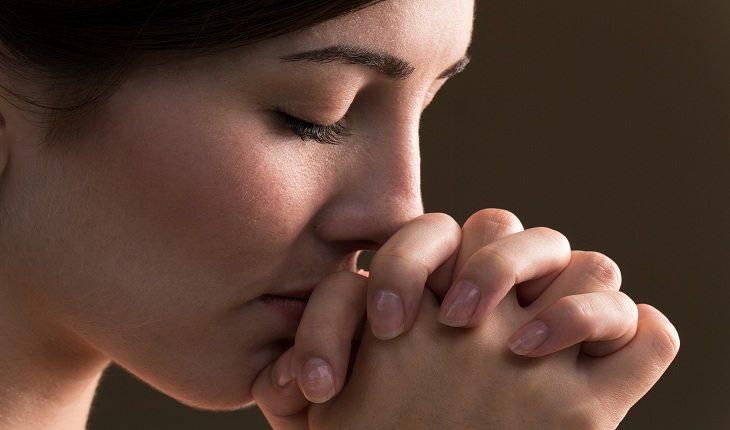 mulher de olhos fechados e fazendo uma oração