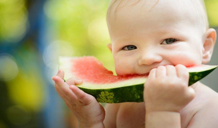 bebê sorrindo enquanto come melancia