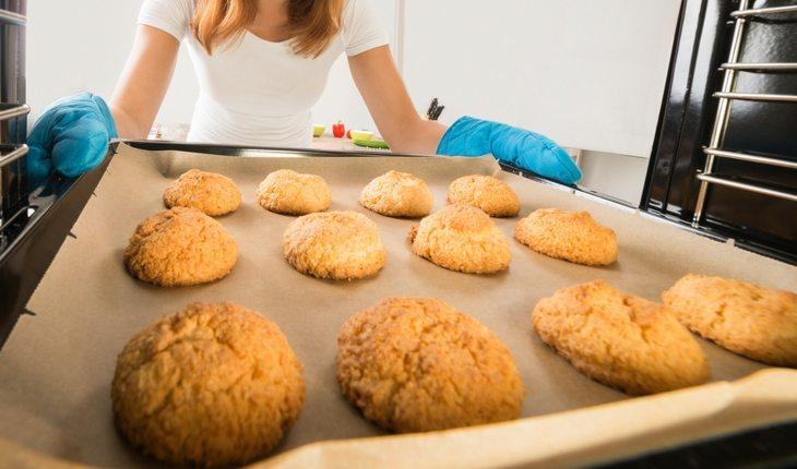 mulher retirando biscoitos assados do forno