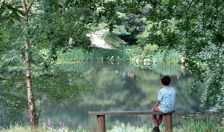 Criança sentada no banco olhando a paisagem