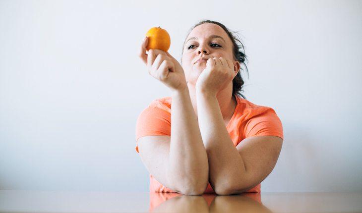 Mitos e Verdades sobre jejum. Na foto, uma mulher olhando uma laranja