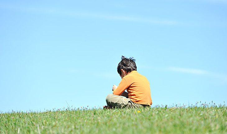 menino sentado sozinho por ter sofrido bullying
