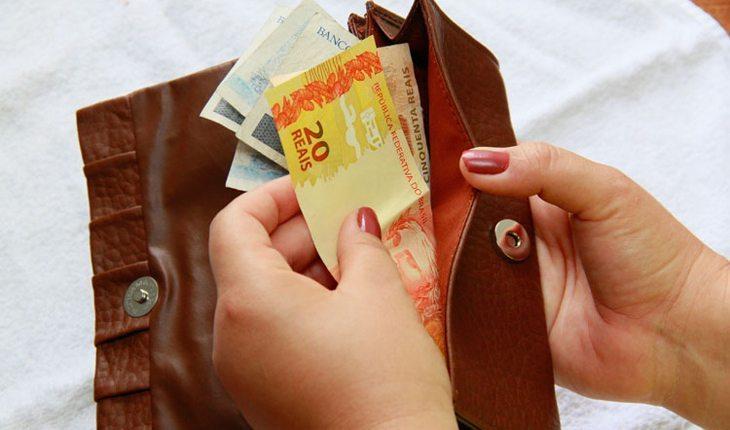 mulher tirando notas de dinheiro de dentro de uma carteira