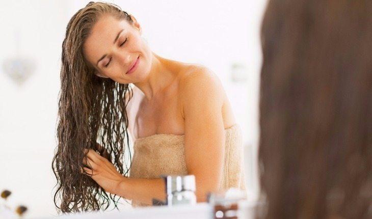 mulher passando produtos no cabelo molhado após sair do banho