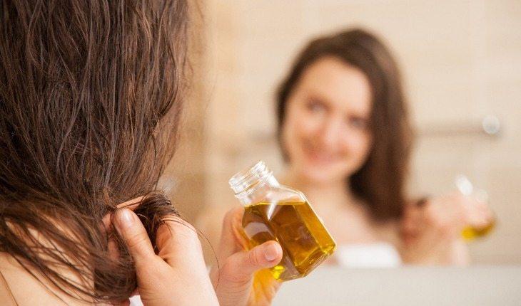 mulher passando óleo vegetal nos cabelos