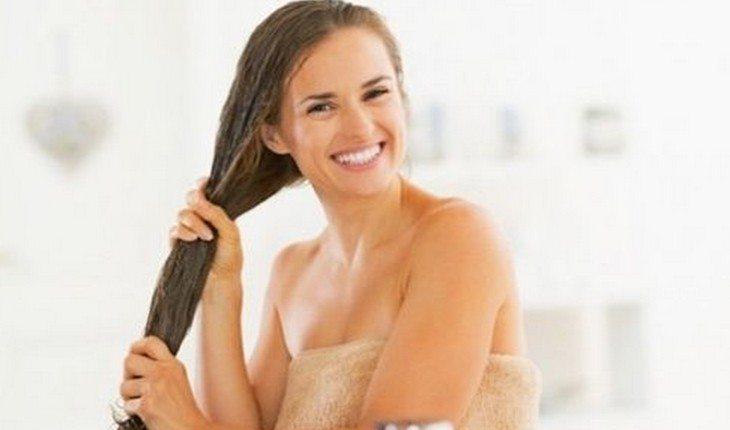 mulher passando creme no cabelo comprido e molhado