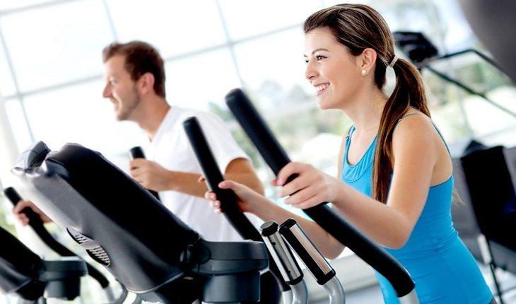 mulher e homem se exercitando em aparelhos de academia