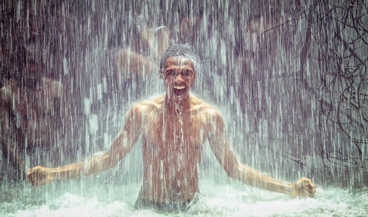 Na imagem, o homem toma banho de chuva no lago sorrindo. Falta de higiene.