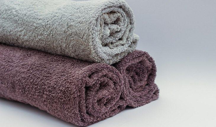 Na imagem, três toalhas estão dispostas juntas em uma superfície branca. Falta de higiene.