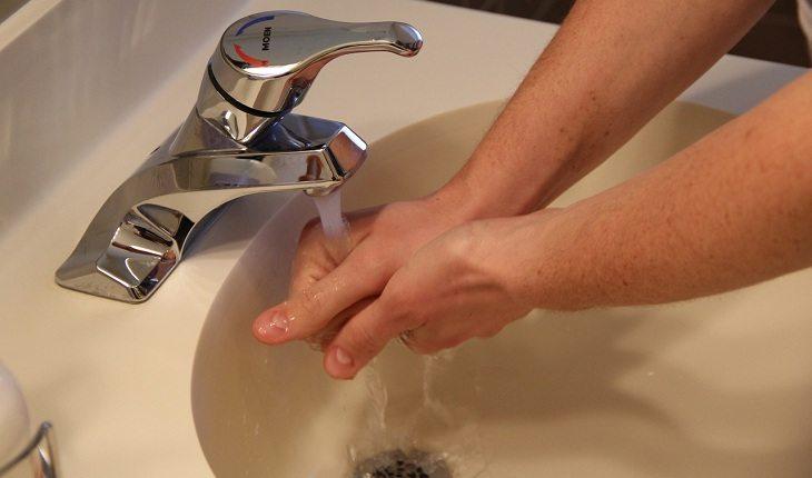 Na imagem, um homem lava as mãos na torneira. Falta de higiene.