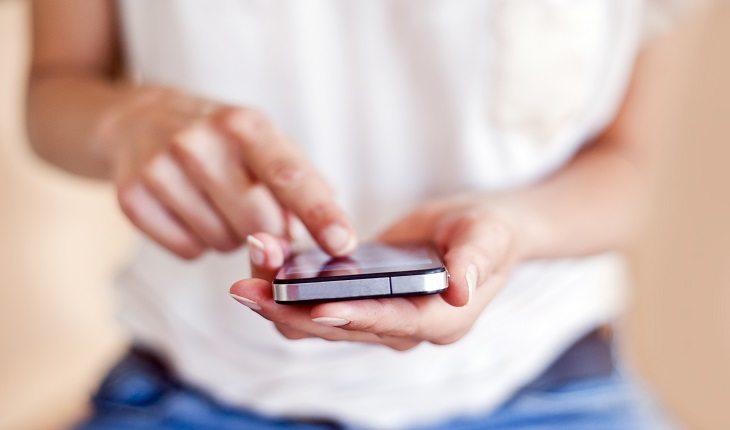 mulher segurando e digitando em um smartphone vestindo uma blusa branca e calça jeans Instagram mais seguro