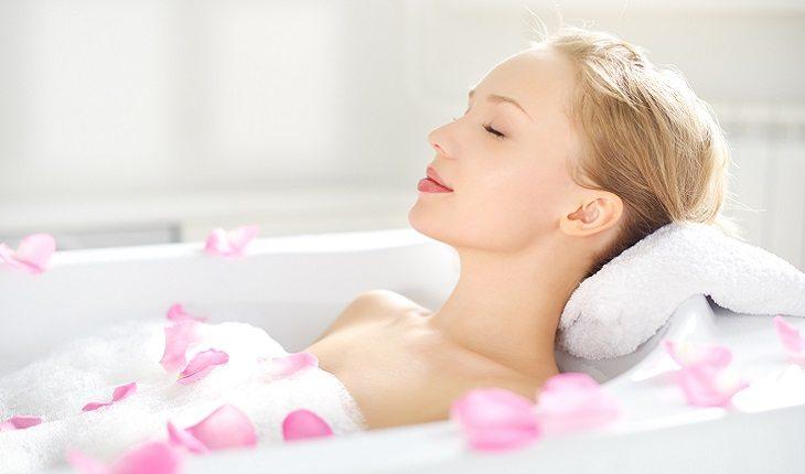 mulher tomando banho de banheira com pétalas de rosas