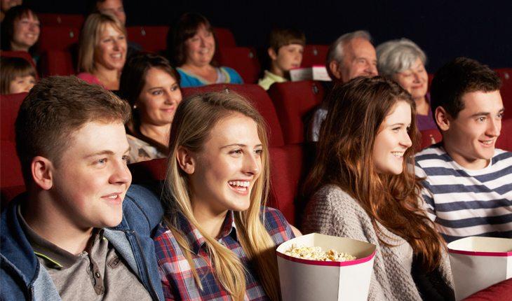 Pessoas sentadas assistindo filme em sessão de cinema