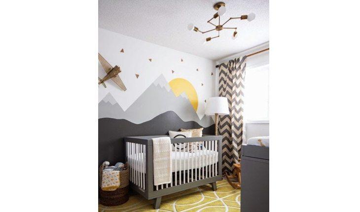 quarto de bebe com um berço preto, parede pintada com montanhas e estrelas. O tapete é amarelo