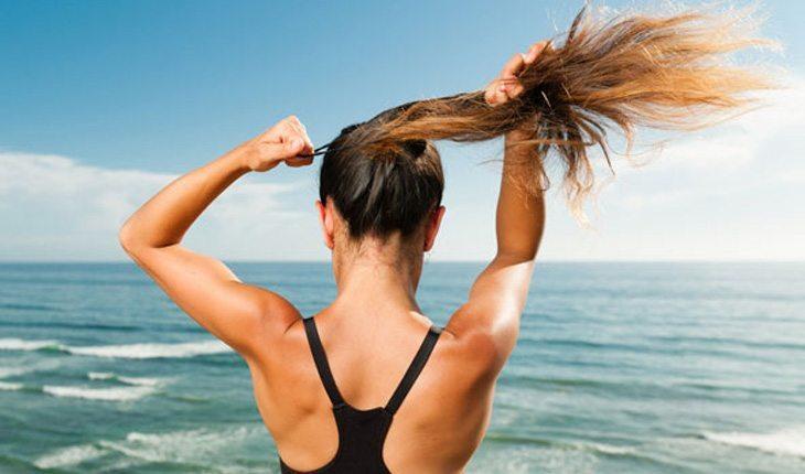 mulher pretendo os cabelos na praia