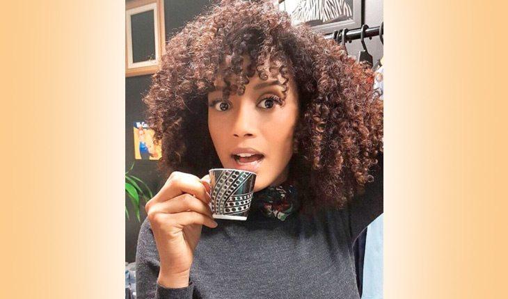 Tais Araújo fala sobre racismo. Na foto, a atriz está com uma blusa preta e segurando uma xícara de café