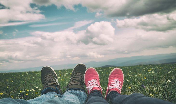 foto mostrando somente os pés de um casal, deitado na grama, contemplando o céu