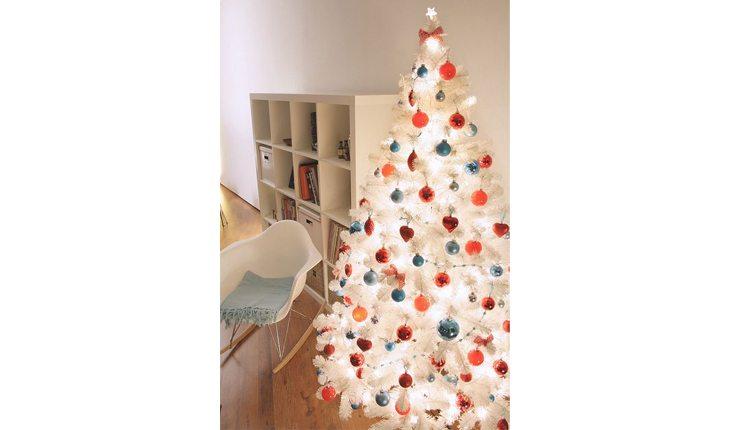árvore de natal branca decorada com enfeites azuis, vermelhos, laranjas e dourados
