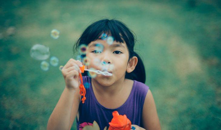 Atividades refrescantes. Na foto, uma menina brincando com bolha de sabão