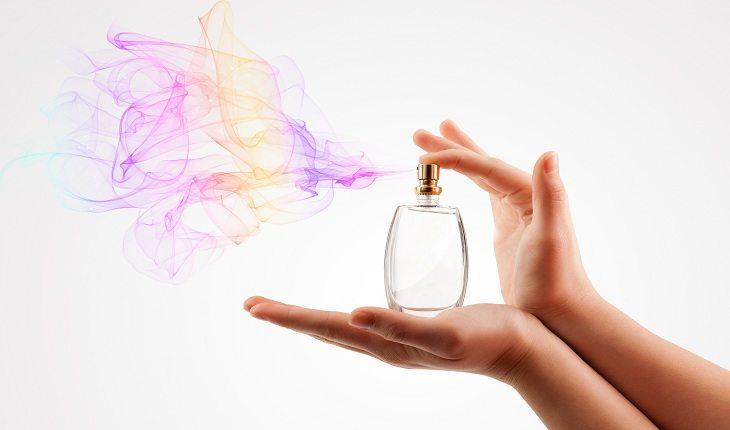 mão de mulher espirrando perfume no ar