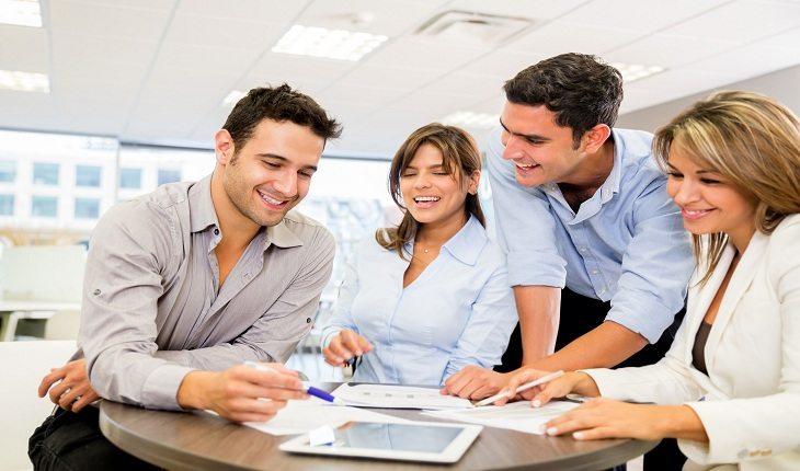 foto de quatro colegas de trabalho sorrindo durante uma reunião de negócios
