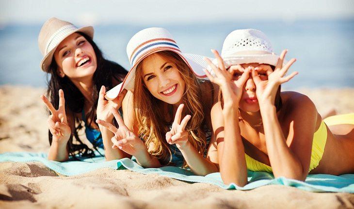 mulheres felizes se protegem do sol com chapéus