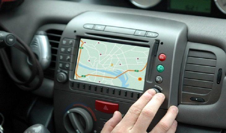 pessoa apertando um botão do painel de GPS em um carro
