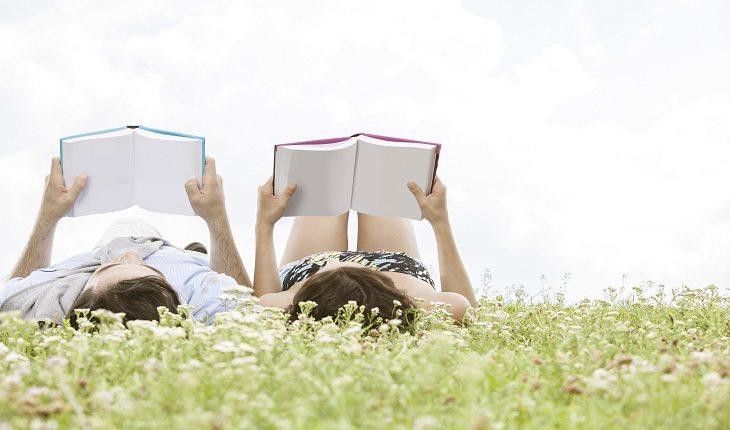 foto de um casal deitado na grama, cada um lendo seu livro