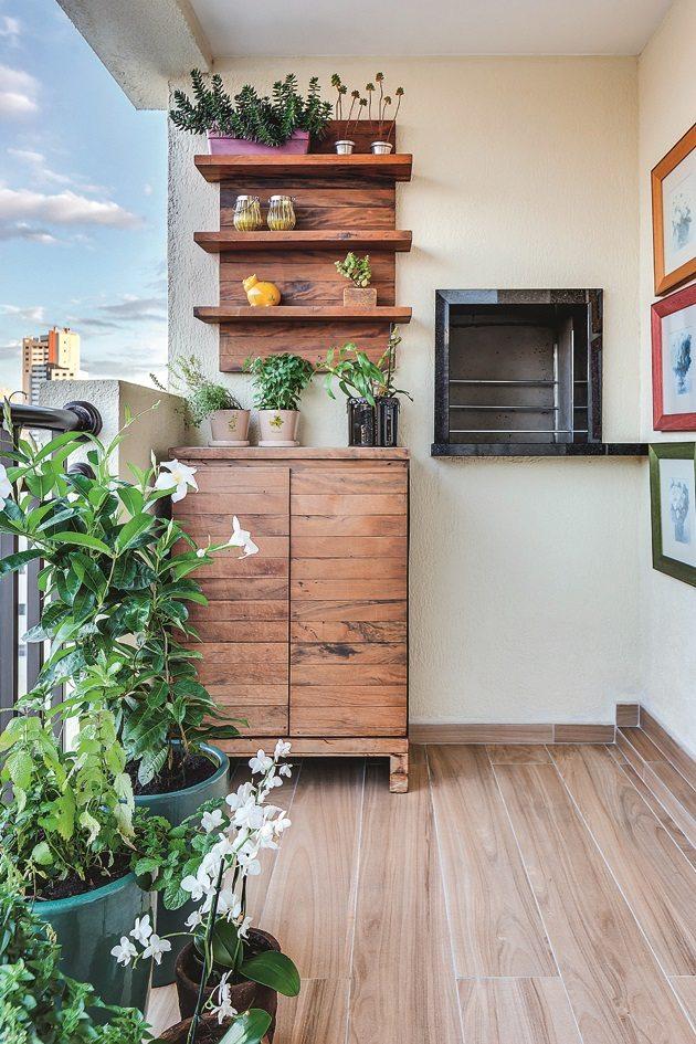 Uma varanda com vasos de plantas no chão do lado esquerdo e no fundo várias estantes suspensas com vasinhos de plantas que ficam ao lado da churrasqueira.