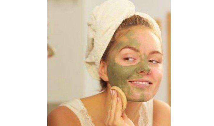 Mulher passando argila verde no rosto.