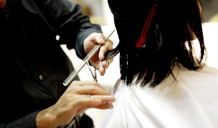 mulher cortando o cabelo no salão com tesoura
