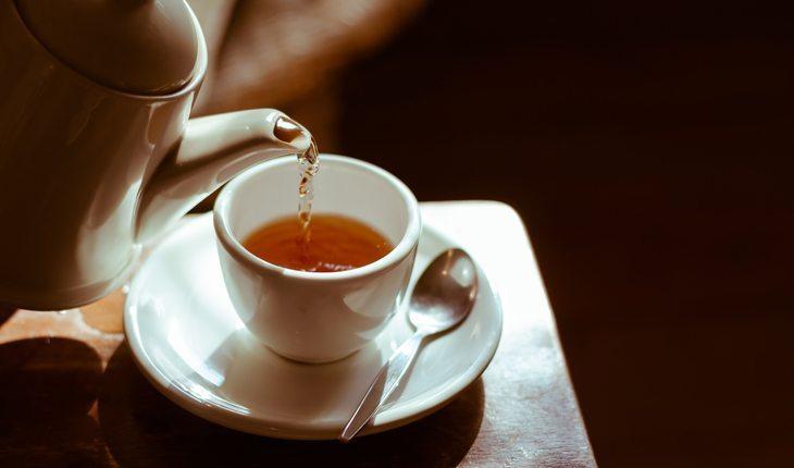 chá de canela sendo colocado em uma xícara branca