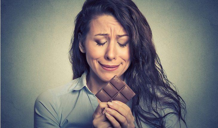 mulher triste comendo chocolate