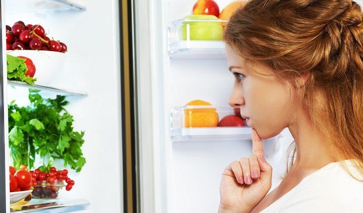 mulher em frente a geladeira escolhe comida com colágeno