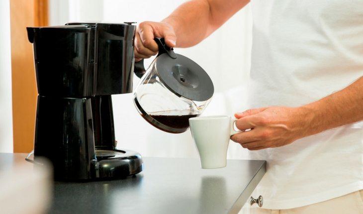 Homem colocando café de cafeteira em xícara branca