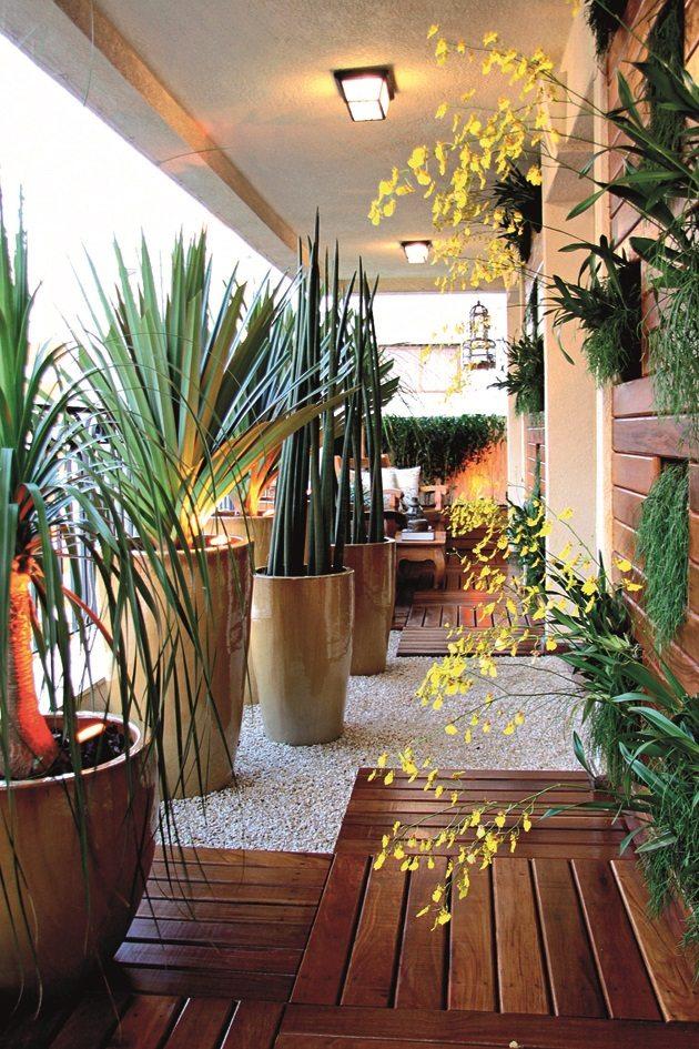 Uma simples varanda com toda revestida com vasos grandes de plantas do lado esquerdo e do lado direito plantas em pequenos vasos pendurados na parede.