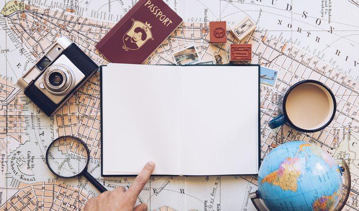 Viajar sozinho. Na foto, um caderno e um mapa do mundo