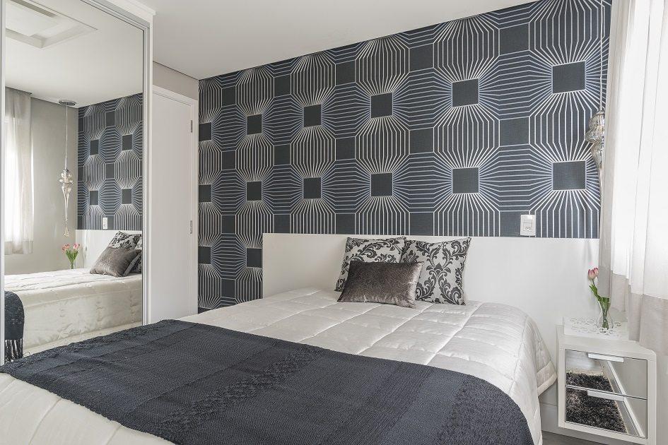 Um dos quartos de casais com cama de casal que fica de costas para uma parede revestida de papel de parede azul e branco.