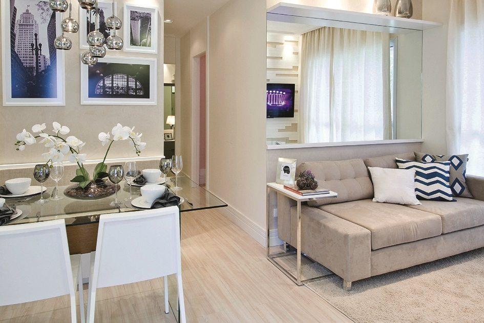 A decoração de ambientes integrados uniu a sala de tv com a de jantar com móveis de tons neutros, como branco nas cadeiras e bege no sofá.
