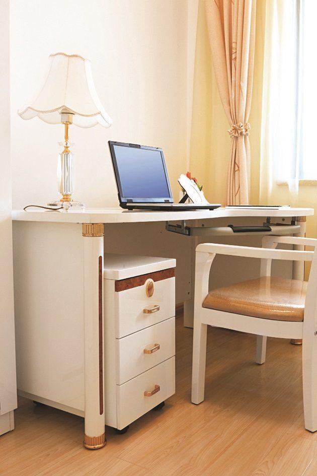 Trabalhe em casa em um espaço com uma mesa branca com um abajur vintage e uma cadeira de madeira com estofado bege.