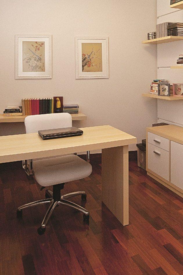 Trabalhe em casa em um uma mesa de madeira com uma cadeira branca e atrás uma bancada com livros coloridos que são destaque ao cômodo.
